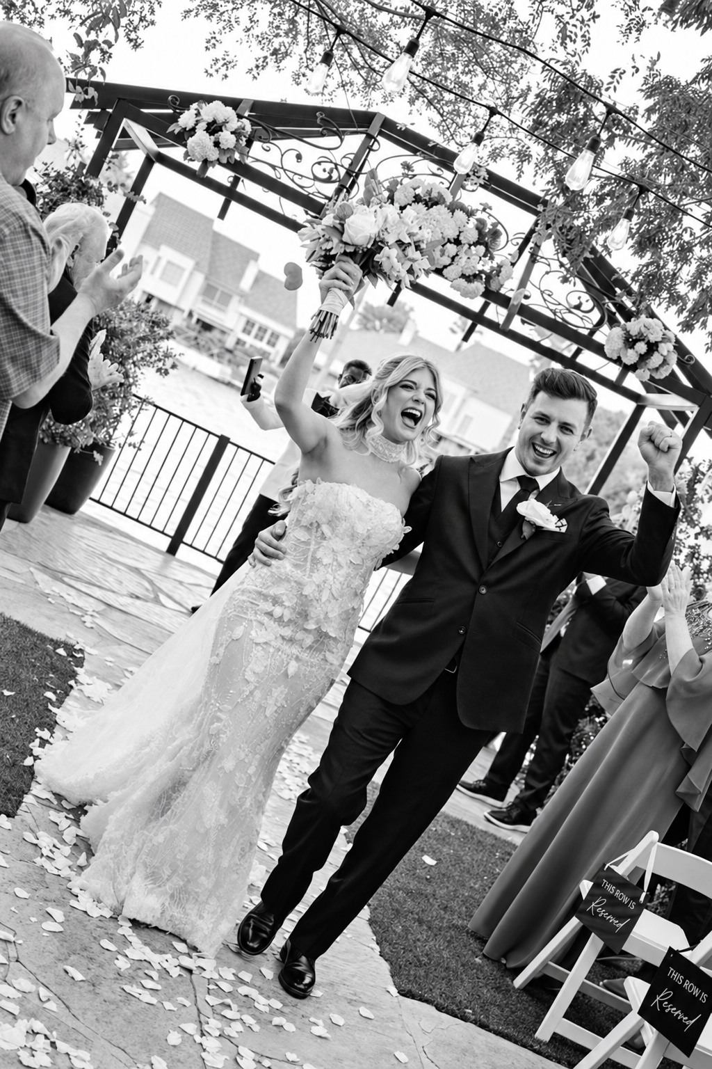 Newlyweds celebrating after the ceremony, with the groom in a custom black suit