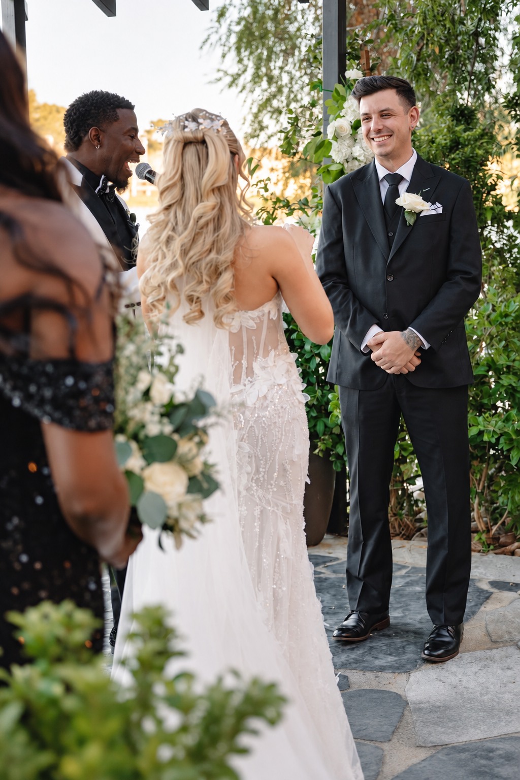 Groom in a custom black suit smiling during his wedding ceremony
